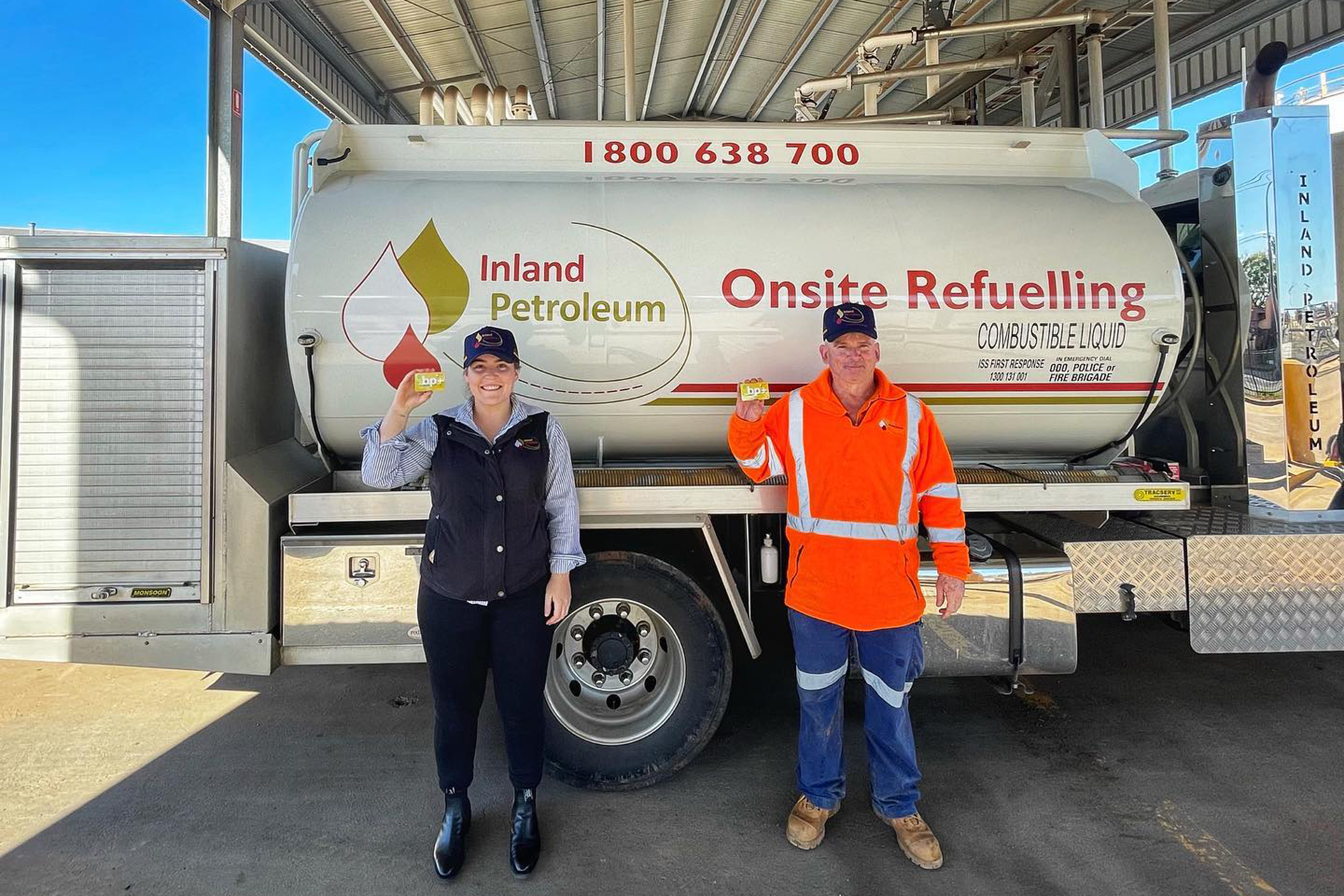 Team members standing in front of fuel tank holding account cards